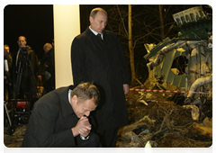 Russian Prime Minister Vladimir Putin and Polish Prime Minister Donald Tusk lay flowers next to a piece of the wreckage from the Tu-154 plane crash