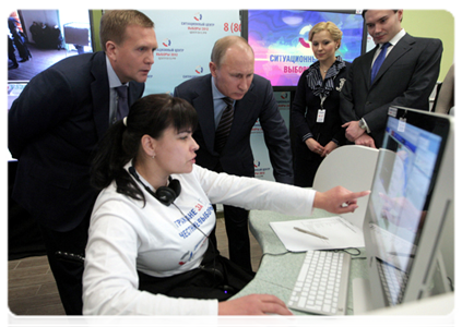 Vladimir Putin reviews the system for the webcam monitoring of polling stations during his visit to the 2012 election monitoring centre